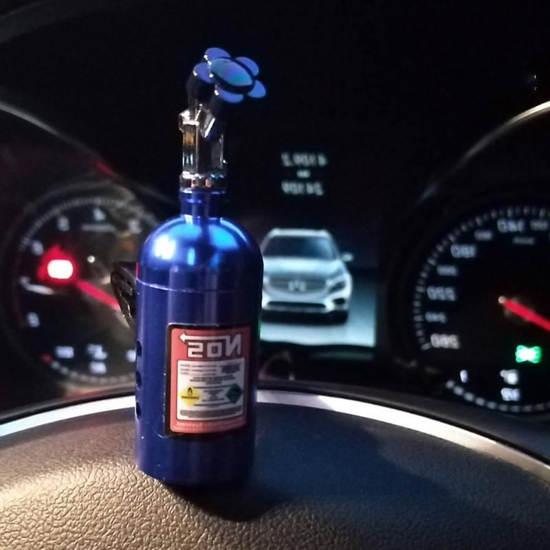 blue NOS nitrous bottle air freshener on car dashboard at night